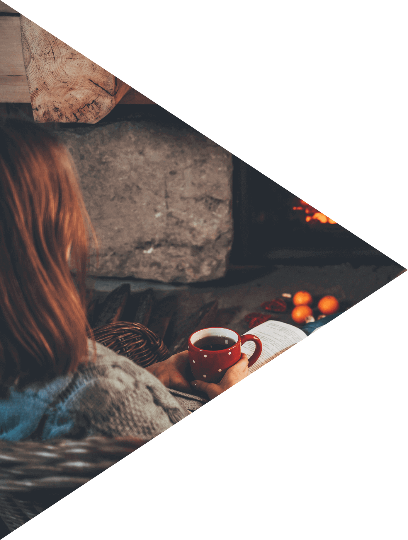 Woman in woollen socks by the fireplace. Unrecognisable relaxes by warm fire with a cup of hot drink and interesting book, warming up her feet.