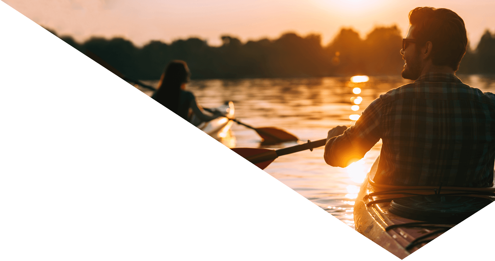 A young couple kayaking on a lake together with sunset in the background